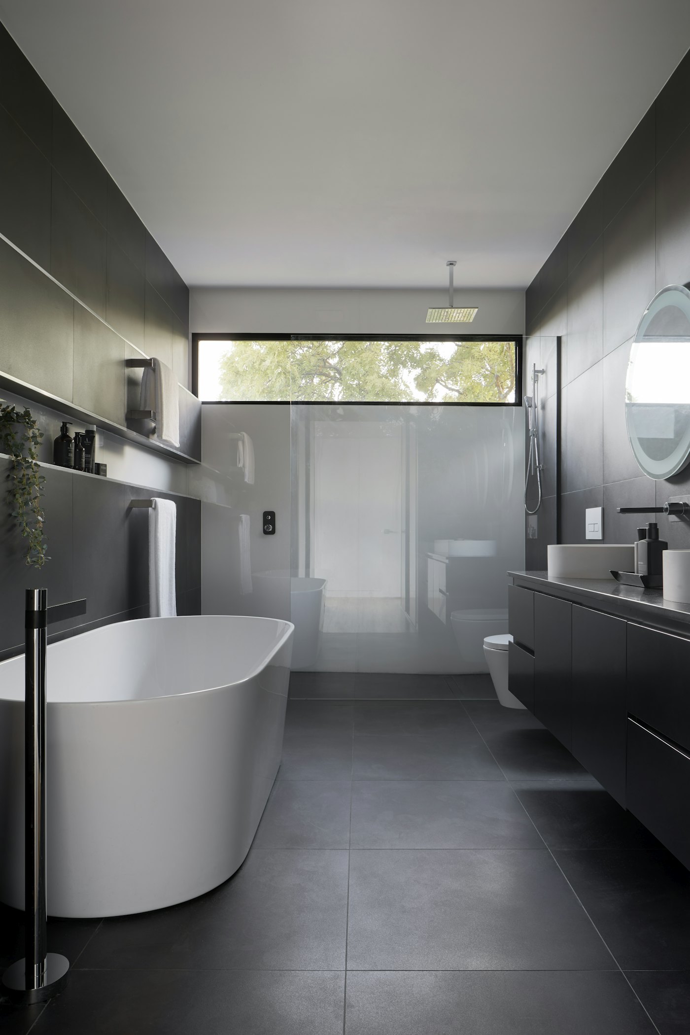 Grey bathroom with a freestanding tub under a clerestory window