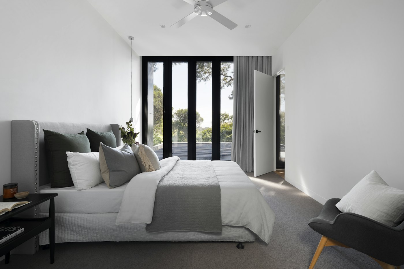 Minimal bedroom with white bedding and black-framed glazing