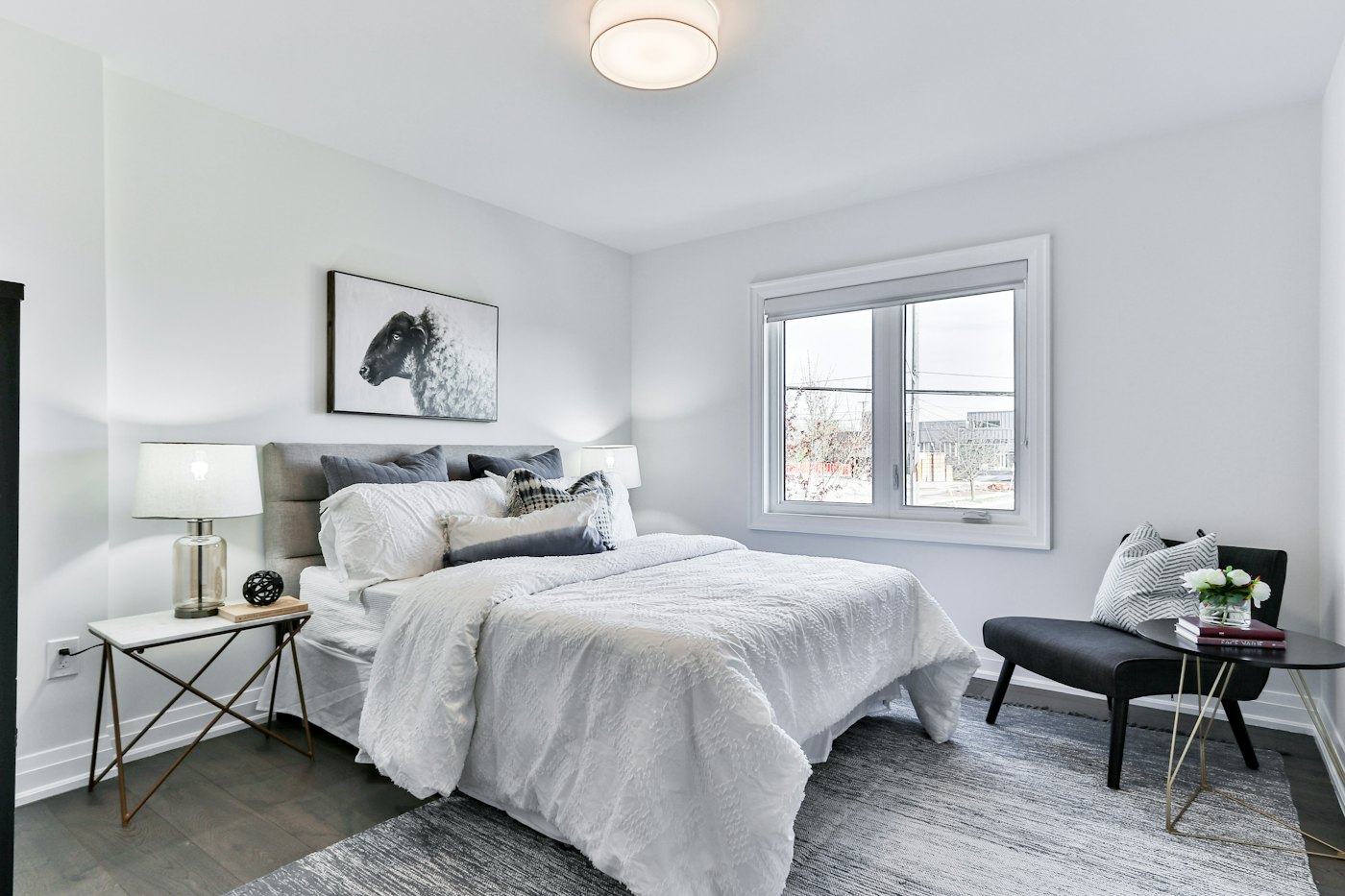 Bright bedroom with white bedding and a lounge chair by the window