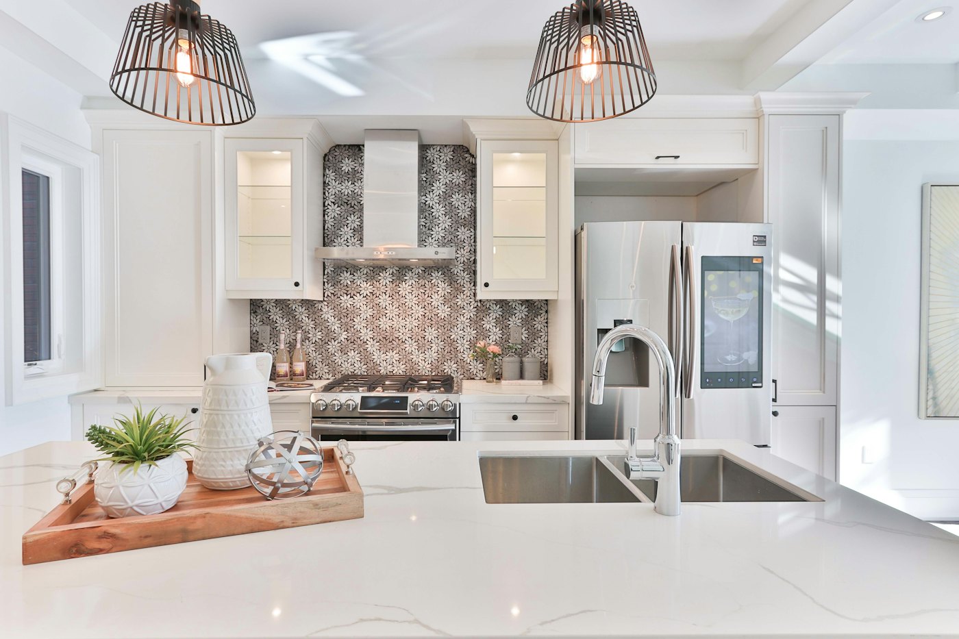 White kitchen with a patterned backsplash, cage pendants and a breakfast island