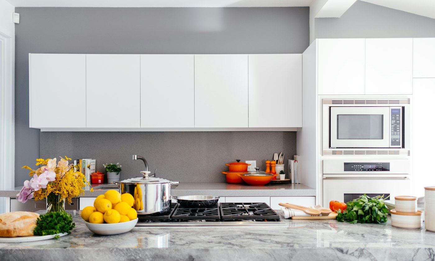 Handleless white kitchen with a grey backsplash and built-in oven tower