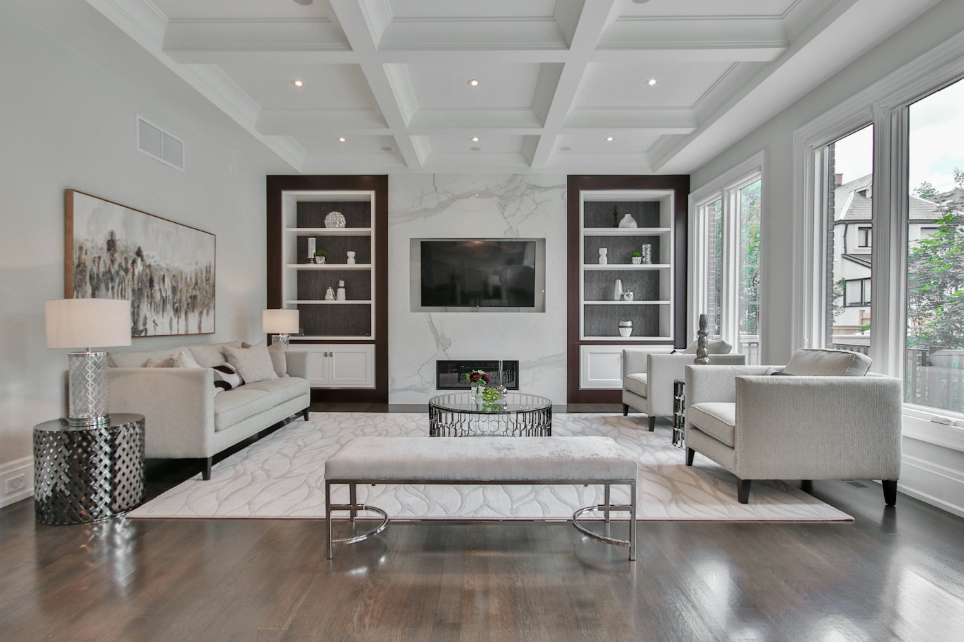 Living room with built-in shelving flanking a wall-mounted TV under a coffered ceiling