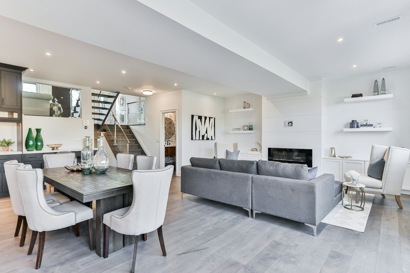 Open-plan living and dining area with a grey sofa and white dining chairs