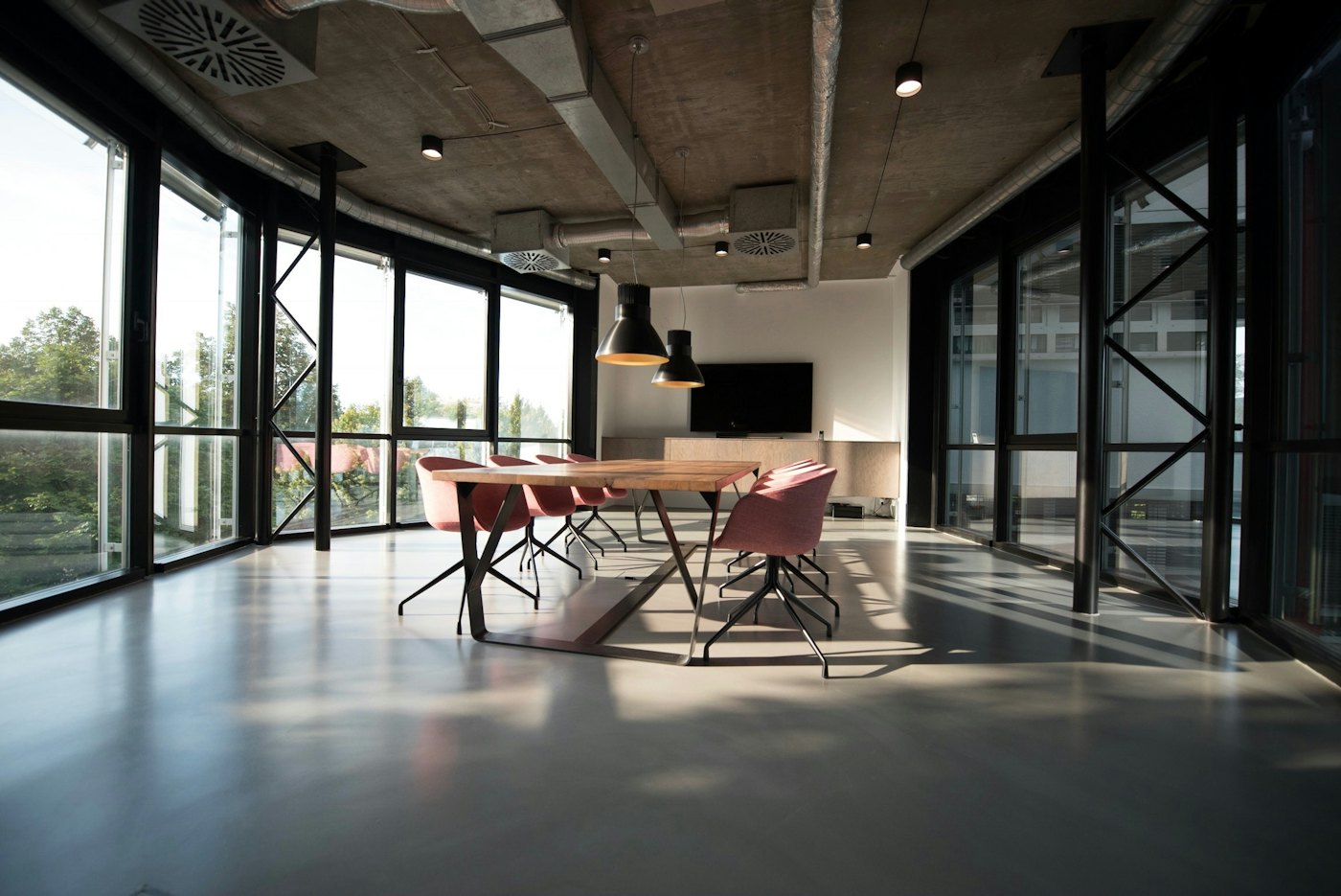 Open-plan office with a long work table and black-framed glazing