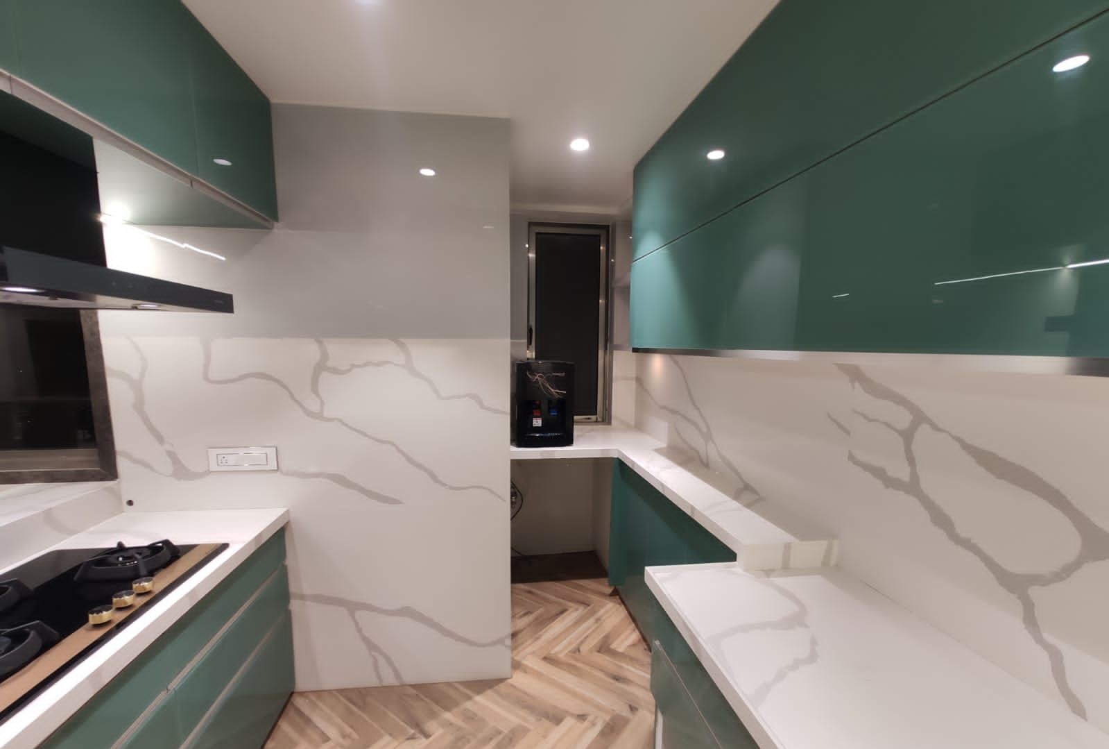 Hob and marble-look backsplash under emerald glass wall units