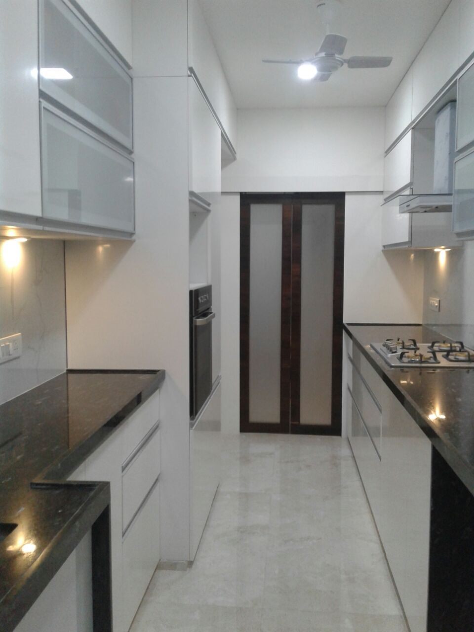 Parallel white high-gloss laminate kitchen with black granite counters
